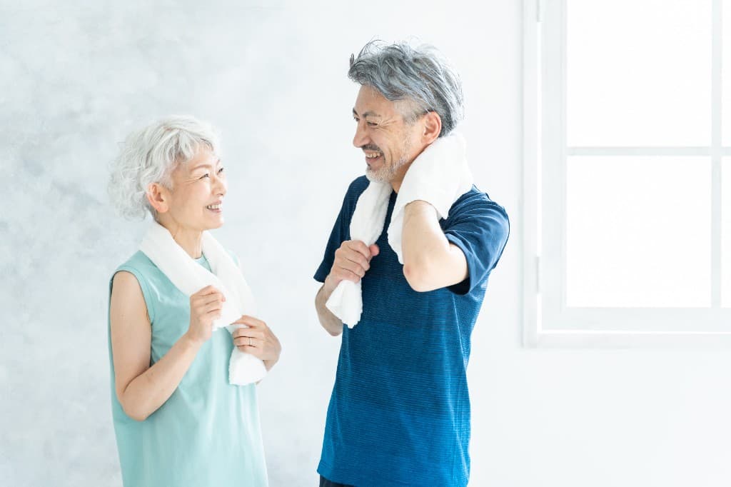 タオルを肩にかけ笑顔で向き合うシニア世代の男女